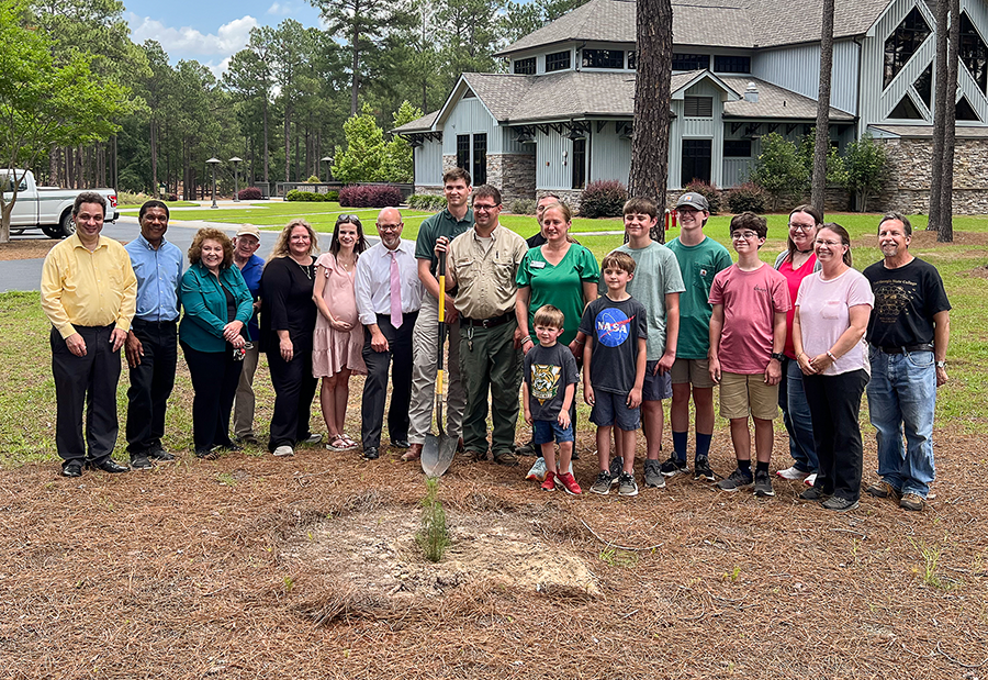 Group stands with newly-planted moon tree